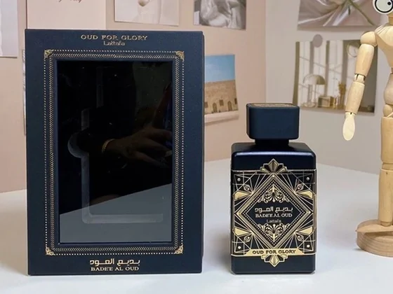A black and gold square perfume bottle standing next to its open box